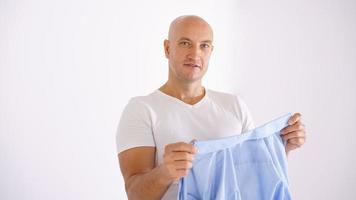 A bald man holding a clean shirt on a white background photo