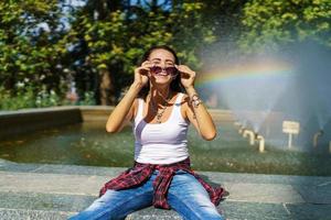 Happy girl posing against background fountain on sunny day in casual clothes photo