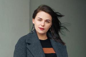 Portrait of a cute woman in the wind in a coat on the street, photo