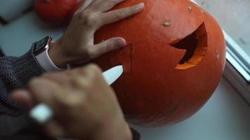 vicino su su mani e coltello intaglio un' zucca video