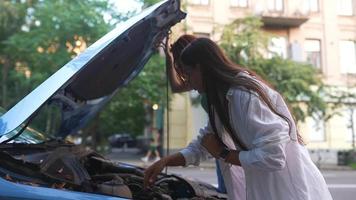 Two young women look under the hood of a car