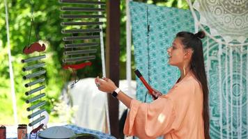 Woman plays vertical swinging chimes instrument outside video