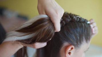 Girls braiding hair with a white strand of hair video
