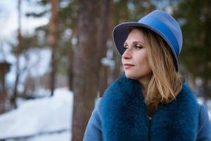 bella mujer con abrigo azul y sombrero posando al aire libre en la nieve foto