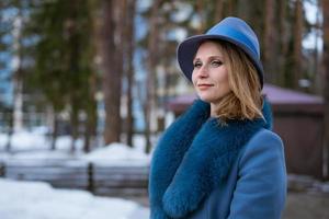 bella mujer con abrigo azul y sombrero posando al aire libre en la nieve foto