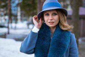 bella mujer con abrigo azul y sombrero posando al aire libre en la nieve foto