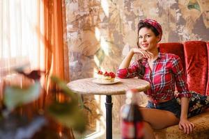 hermosa pin-up mujer sentada en una mesa en un café foto