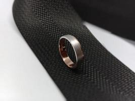 un anillo de bodas y un anillo de compromiso con material de oro rosa con una variación blanca de mutilación que se coloca en una correa de bolso negra foto