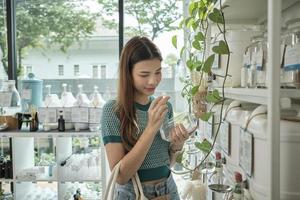 A White female customer smells organic merchandise, chooses and shops for appliance products in refill store, zero-waste grocery, reusable containers, and environment-friendly, sustainable lifestyle. photo