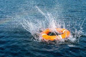 Orange lifebuoy in the sea. The rescue ring fell with a splash on the surface of the water, motion blur . photo