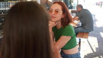 Two women talk and hang out at sunny coffee shop video