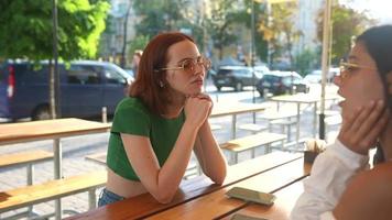 Two women talk and hang out at sunny coffee shop video