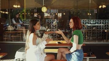 Two women talk and hang out at sunny coffee shop video