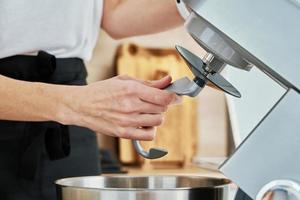 Woman put in hook nozzle in electric mixer photo