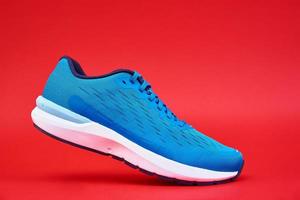 Blue running sneaker on red background, close up photo