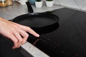 Woman hand turns on modern induction stove in the kitchen photo