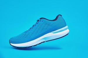 Blue running sneaker on blue background, close up photo