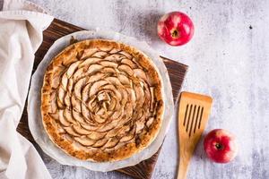 Baked apple tart on baking paper on the table. Homemade baking. Top view photo