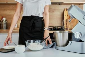 Woman cooking at kitchen and using kitchen machine photo