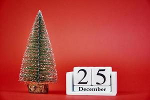 Merry Christmas and Happy New Year composition with christmas tree on red background photo