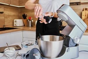 Woman cooking at kitchen and using kitchen machine photo