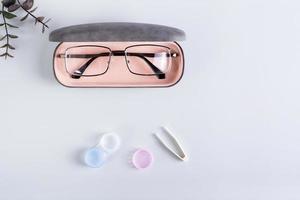 A case with glasses, an open container with contact lenses and tweezers. Top view. photo