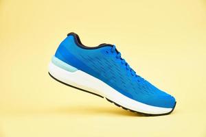 Blue running sneaker on yellow background, close up photo