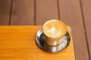 Hot coffee latte art foam on wooden table. photo