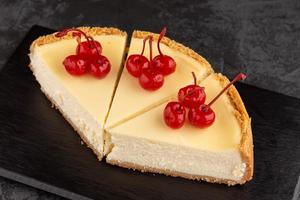 classic cheesecake decorated with cherries on a dark background photo