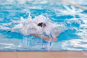 un nadador beanie estira los brazos durante un entrenamiento de braza en la piscina, enfoque borroso foto