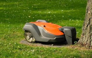 Robotic Lawn Mower on green grass background.Automatic robot lawnmower in modern garden.Green grass trimming with lawn mower. Close-up view of the lawn mower dirty blade after mowing the lawn. photo