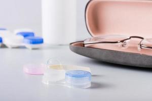 Contact lens on an open storage container against the background of a case with glasses photo