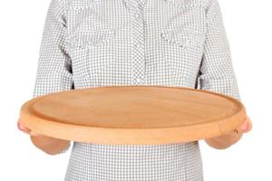 la chica de la camisa a cuadros sostiene un plato redondo vacío de madera para pizza frente a ella. mano de mujer sostenga el plato vacío para su diseño. vista en perspectiva, aislada sobre fondo blanco foto