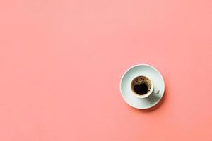 taza de café azul sobre un fondo rosa colorido. vista superior con espacio de copia. concepto de la mañana foto