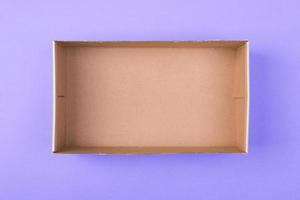 empty cardboard paper box on purple background. delivery concept, top view photo