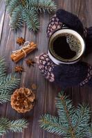 Female hands holding mug of hot chocolate coffee on rustic wooden background with Christmas fir tree branch, copy space. winter hot drink concept photo