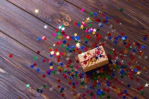 Gift box with star. Creative concept with festive decor on black background. Confetti stars, red, yellow with gift box. Explosion of confetti photo