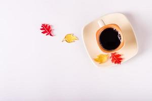 Autumn still life cup of black coffee and colored leaves on a pink background. Top view. Copy space photo