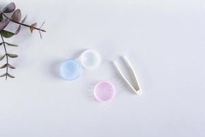 An open container with contact lenses and tweezers on a blue background. Top view. photo