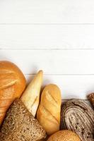 Assortment of baked bread on wooden table background. top view with copy space photo