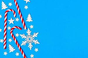 Christmas candy cane lied evenly in row on blue background with decorative snowflake and star. Flat lay and top view photo