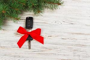 gift for christmas car keys. Close-up view of car keys with red bow as present on wooden background photo