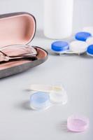 Contact lens on an open storage container on the background of a case with glasses. Vertical view photo