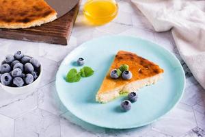 A piece of cheesecake with honey and blueberries on a plate on the table. Homemade pastries photo