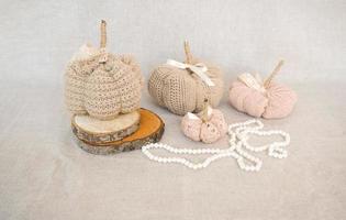 Hobby background with handmade knit pumpkins and white pearl beads. DIY, craft decoration for fall and winter holidays. photo