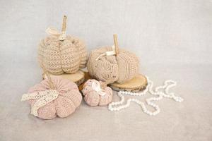 Hobby background with handmade knit pumpkins and white pearl beads. DIY, craft decoration for fall and winter holidays. photo