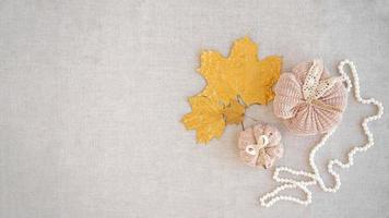 Hobby background with handmade knit pumpkins and golden maple leaves. DIY, craft decoration for fall and winter holidays. Flat lay, top view photo