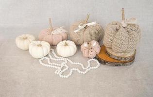 Hobby background with handmade knit pumpkins and white pearl beads. DIY, craft decoration for fall and winter holidays. photo