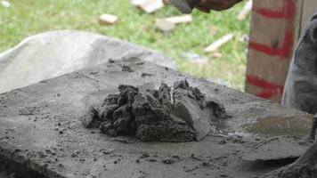 Hand eines Bauarbeiters, der Zement und Sand mit einer Schaufel mischt video