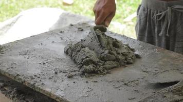 Hand eines Bauarbeiters, der Zement und Sand mit einer Schaufel mischt video